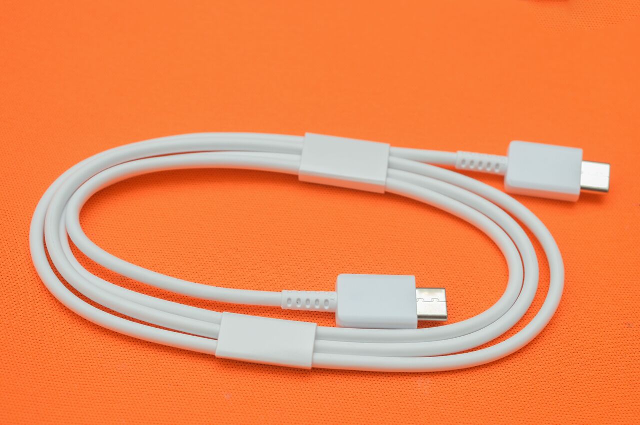 オレンジ色の背景に白い USB-C ケーブル