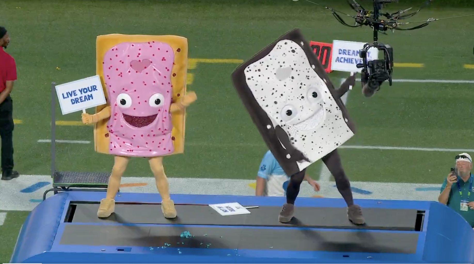 팝타르트 마스코트 의상을 입은 두 사람이 축구 경기 플랫폼에 서 있습니다.