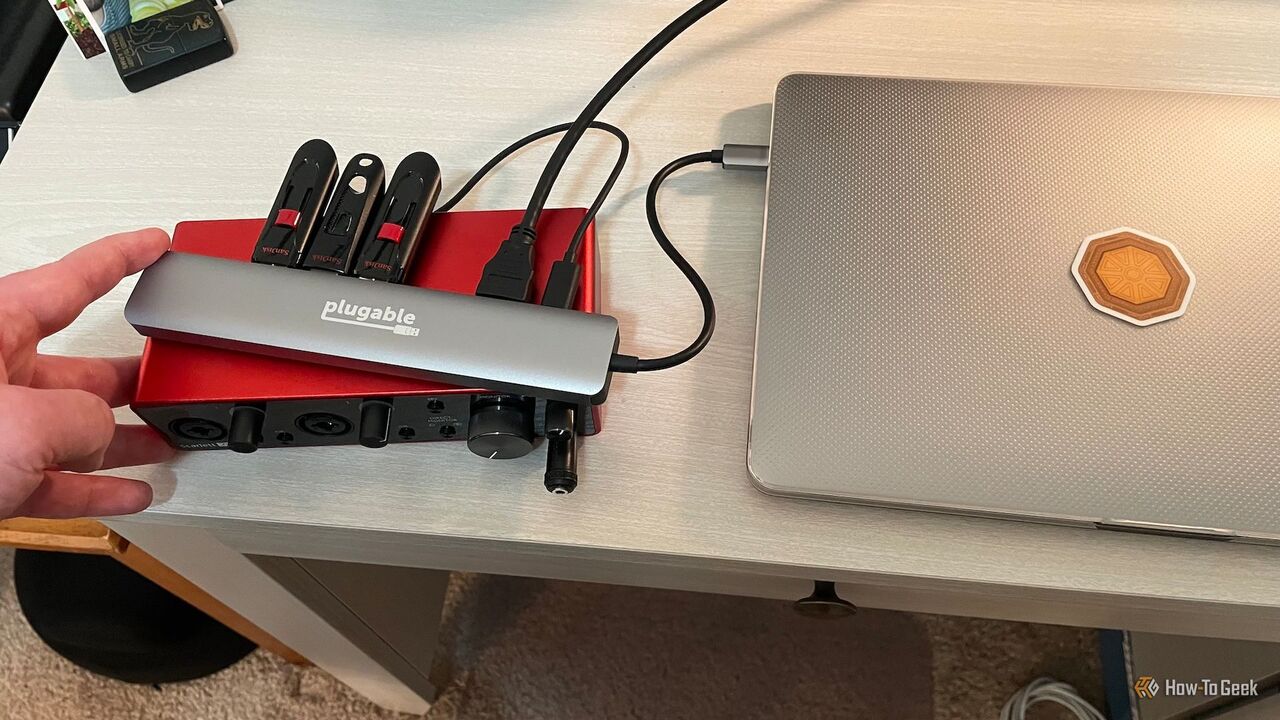 Plugable 9-in-1 USB-C ハブに接続されたラップトップ、3 つの外部フラッシュ ドライブ、および録音インターフェイス。