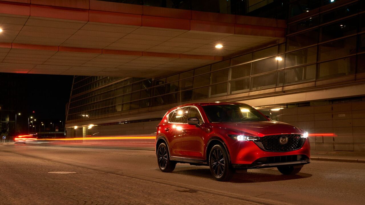 夜間に地下道を走行する赤い 2025 型マツダ CX-5 の正面からの 4 分の 3 のビュー。