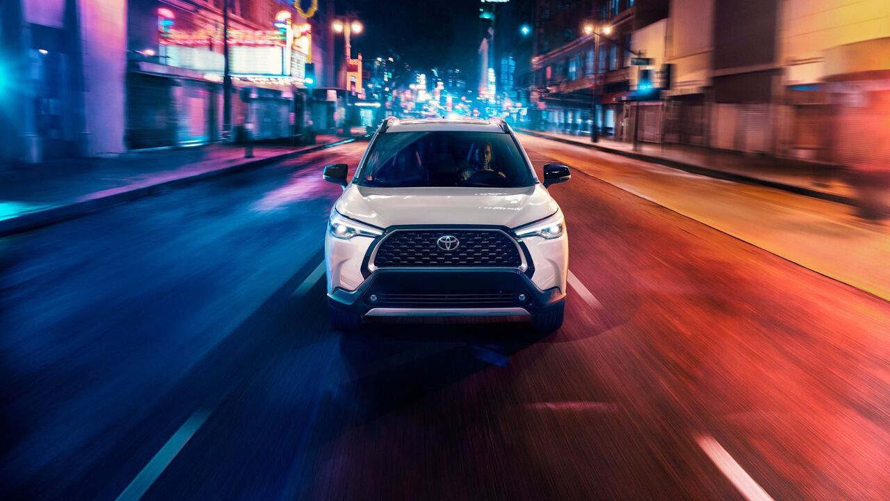 白い 2025 トヨタ カローラ クロス ハイブリッド XSE のダイナミックなフロントエンド ショット。