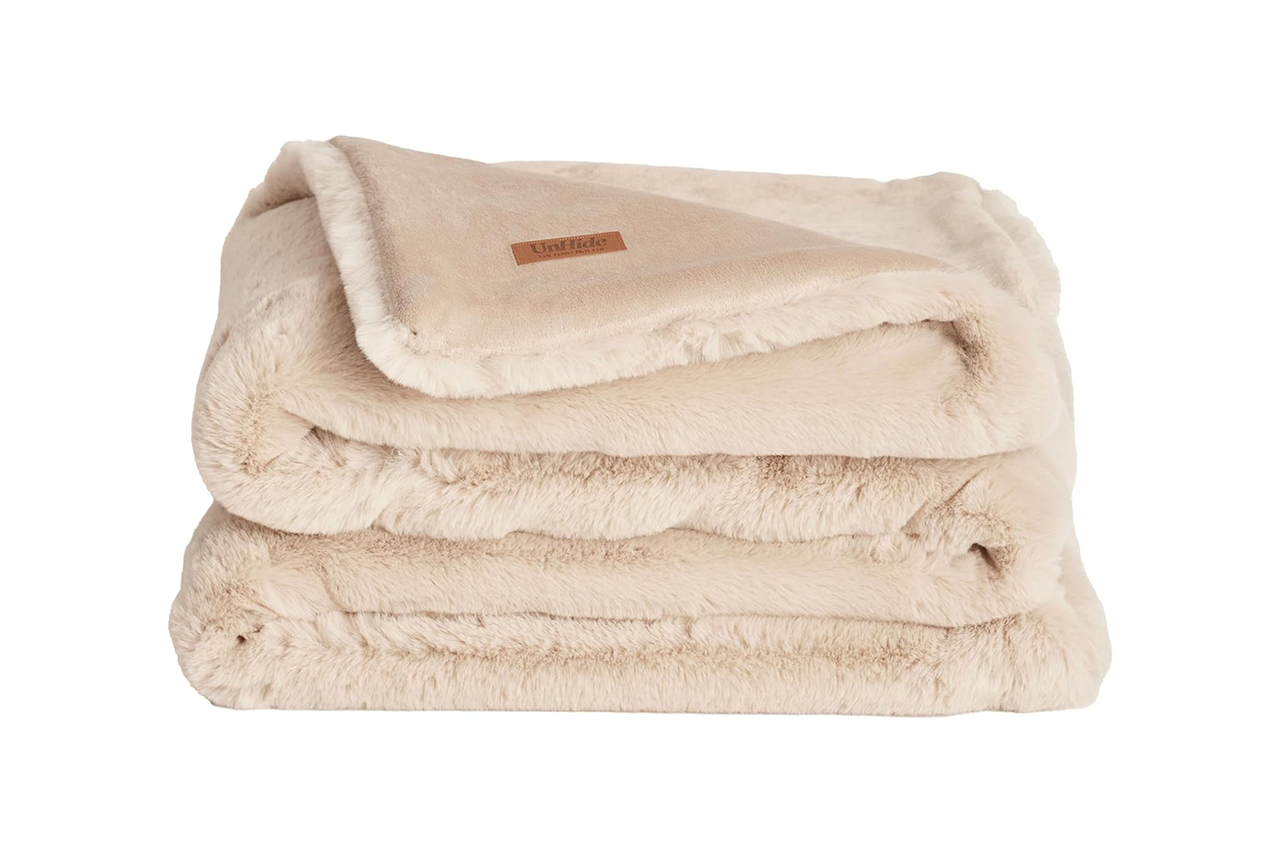 브라운 컬러의 접힌 베이지색 인조 모피 담요 "숨기기 해제" 상표.