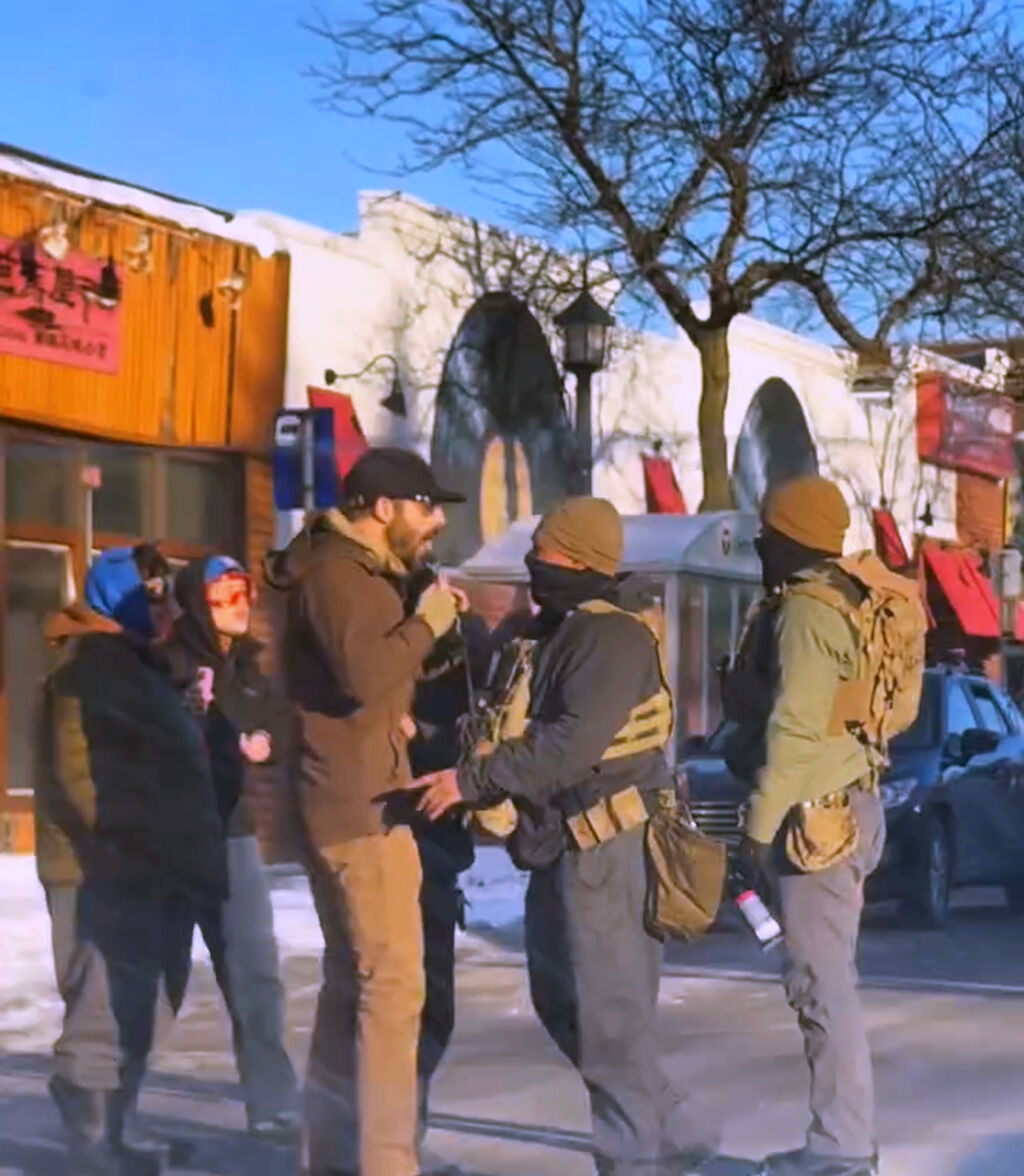 눈 덮인 건물을 배경으로 한 거리에서 시위대와 연방 요원을 포함한 한 무리의 사람들이 서로 마주보고 있습니다.