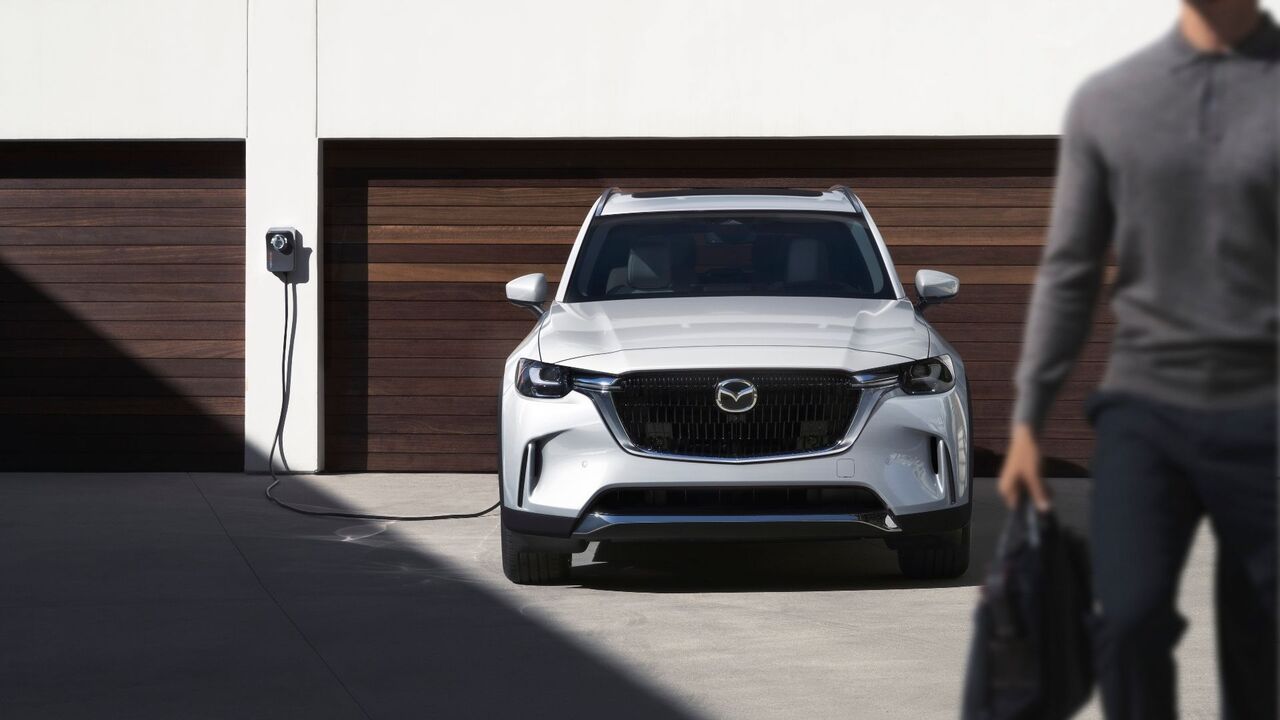 充電に接続された白い 2026 マツダ CX-90 PHEV の静的なフロントエンド ショット。