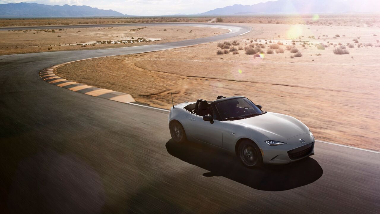 砂漠のレーストラックにあるシルバーの 2024 マツダ MX-5 のダイナミックなフロント 3/4 ショット。