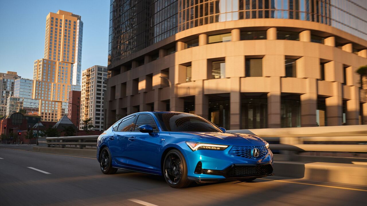 街中を走行する青い 2026 Acura Integra のダイナミックなフロント 3/4 ショット。