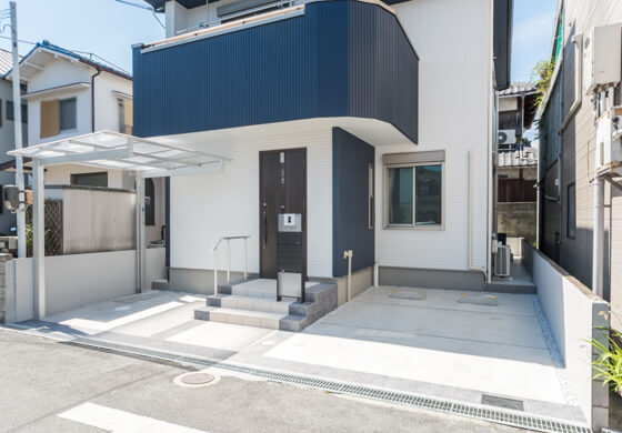 縁どったダークグレーのタイルは、「ニッタイのロマーニⅡ（95）」。中央は「ロマーニⅡ（05）」。道路の境界にも、ダークグレーの95番を使ってラインをいれ、外構の印象を引き締めています。