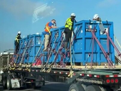 走行中のトレーラーの積荷の上に作業員が立ち乗り、ハーネス1本で高速道路を移動【海外の反応】