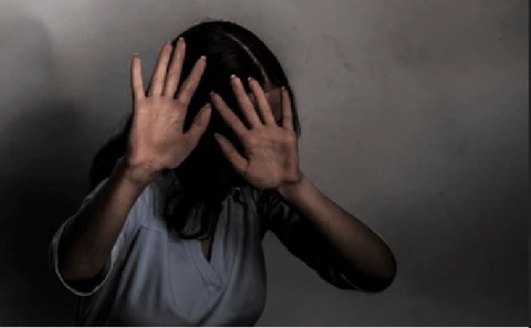 薄闇の中両手で防御する女性