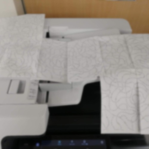 業務用プリンターの上に広げられた紙面