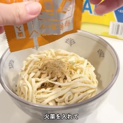 耐熱容器に移したどん兵衛の麺にかやくを入れる様子