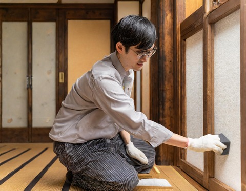 襖の汚れを消しゴムで取っている人