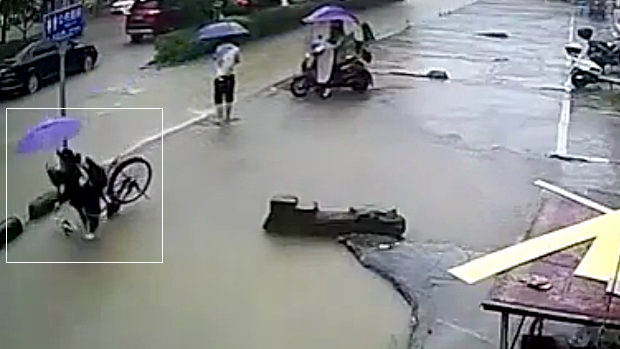 中国、冠水した道路を自転車で走る女性、浅いと思って突っ込んだらドボン！