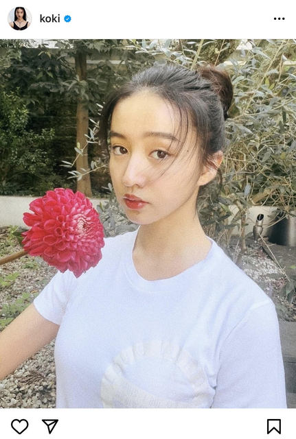 『Koki,』赤い花を手にカメラを見つめる白Tシャツ姿のビューティーショット