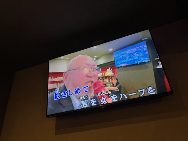 写真29 歌う吉本副理事長を映す