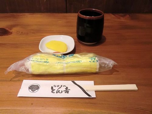 【お食事処 とん吉】〔入店し、「そちらへどうぞ。」と指された場所に着席。お茶・オシボリ・お箸と、お新香も出てきた。店内は、入ってすぐに厨房前のカウンター席、クルっと左に回っていくとテーブル席と小上がりの座敷も。〕 (2)